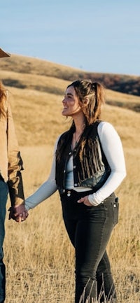 two people in cowboy hats holding hands in a field